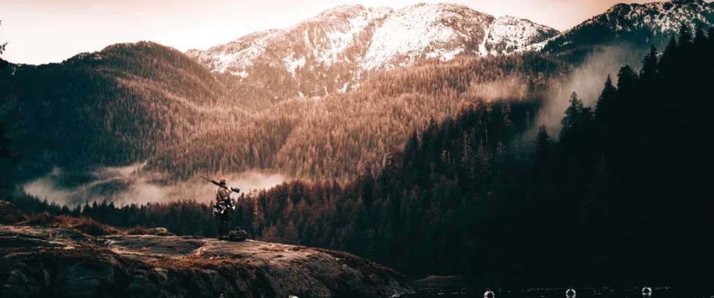 Scenic mountain landscape with pine trees and fog at sunrise, representing Apex Ammunition’s rugged, outdoor hunting environments.